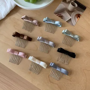 Detailed view of nine colorful satin bow hair combs on a wooden table setup