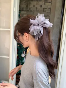 Gros plan d'un grand chouchou en organza lavande avec strass sur des cheveux ondulés