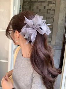 Une modèle élégante portant un grand chouchou en ruban de maille grise et strass.