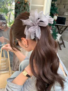 Chouchou élégant en organza avec grand ruban sur longs cheveux ondulés, profil.