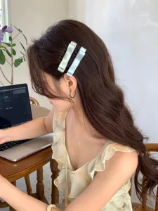 Close-up detail of a girl wearing elegant satin bow hair clips in light green and blue