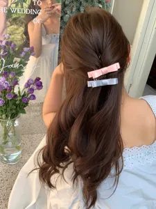 Detailed view of pink and grey bow hair combs styled in a feminine half-up hairdo