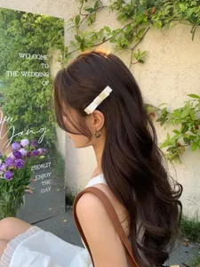 White bow hair clip detail on long wavy hair in a romantic outdoor setting