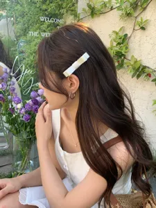Detail view of an elegant white ribbon bow hair clip styled on a model in a garden