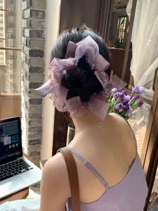 Vue arrière d'une femme portant un grand chouchou en organza violet brillant sur un chignon