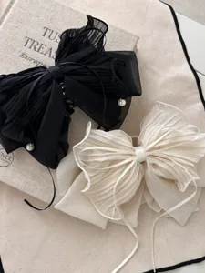 Detailaufnahme eleganter schwarzer und cremefarbener Haarklammern mit Netzschleifen.
