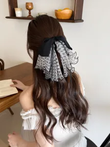 Detail view of a French elegant polka dot mesh bow hair clip worn on wavy hair