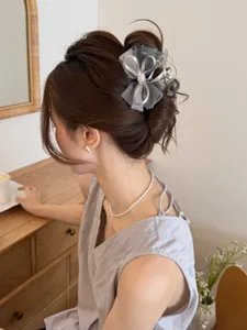 Detalle de una pinza para el pelo con lazo de malla gris, peinado en un moño elegante.