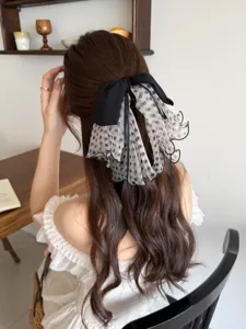 Detail showing the French style polka dot mesh bow hair clip on long wavy brown hair