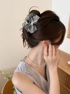 Detalle de una elegante pinza para el pelo con lazo de malla gris y perlas en un recogido