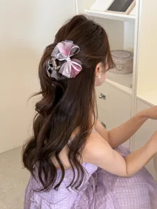 Elegante pinza de pelo con lazo de malla rosa lucida por una modelo en un ambiente chic