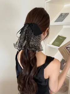 Detail of a French style mesh bow hairclip with leopard print worn on a ponytail.
