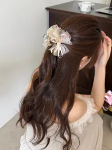 Detalle de una elegante pinza para el pelo con lazo floral en pelo castaño ondulado