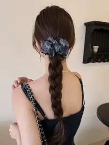 Vue de dos d'une femme portant un chouchou en résille fleurie sur une longue tresse.