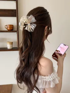 Primer plano de una pinza para el pelo con lazo de malla floral en cabello ondulado