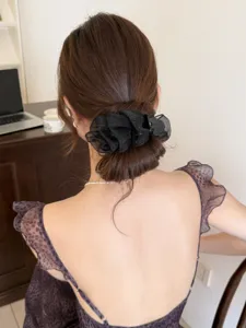 Vue détaillée d'une élégante pince à cheveux en tulle plissé noir sur un chignon.