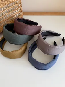 Set of five wide fabric headbands in muted earthy tones like green, blue, and brown.