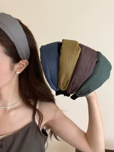 Detail view of various simple cloth wide headbands in assorted natural colors for women.