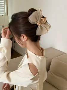 Close-up view of a large milk tea organza bow hair claw clip styled on a woman bun