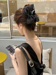 Rear view of model wearing a stylish black organza oversized bow hair claw clip