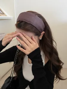 Detail view of a minimalist wide purple fabric headband worn to create a high cranial top