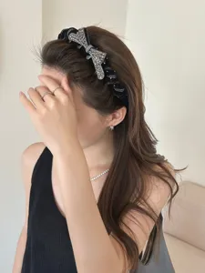 Detailed view of elegant black velvet headband with luxury rhinestone bow on model