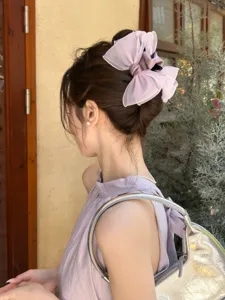 Detailed view of an elegant purple organza bow claw clip adorning a bun hairstyle