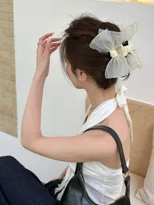 Close-up detail of a milk tea organza bow hair claw clip on a model's updo hairstyle