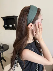 Detailed side view of a minimalist moss green wide fabric headband worn by a woman