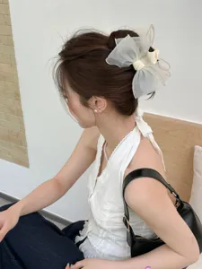 Detail view of the elegant milk tea organza bow hair claw clip on hair bun.