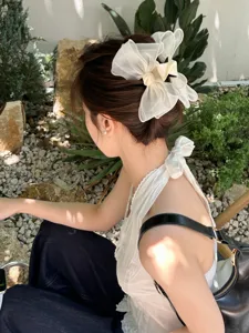 Large white organza bow hair claw clip for elegant bun hairstyle detail view.