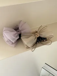 Close-up of elegant organza bow hair claw clips in soft lavender and beige shades