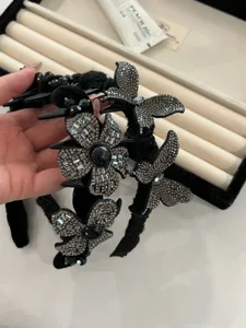 Close-up of black headband featuring sparkling rhinestone butterfly and flower designs.