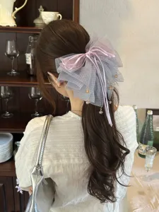 Detalle de pinza para el pelo con lazo de tul de lunares, cintas lilas y colgantes dorados.