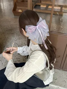 Detalle de la pinza de pelo con lazo de malla púrpura con cintas y colgantes dorados