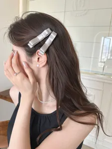 Elegante silberne Haarspangen mit Satin-Schleife, im Detail am braunen Haar gezeigt