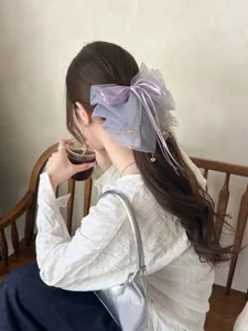 Detalle del lazo de pelo de malla lavanda con lunares y colgantes dorados de moda