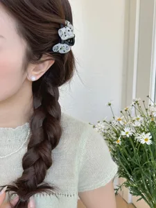 Primo piano di una mini pinza per capelli con fiocco a pois su una treccia da donna.