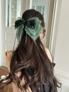 Vista detallada de una pinza para el cabello con lazo verde de lunares y cintas negras.