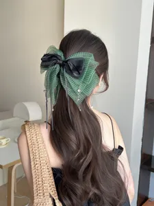 Primer plano de pinza de pelo con lazo verde de lunares, cintas negras y colgantes de cristal