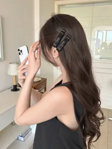 Detailaufnahme von stilvollen schwarzen Satin-Schleifen-Haarspangen in braunem Haar.