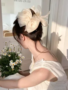 Elegante crèmewitte mesh strik haarklem getoond in een romantisch kapsel detailopname.