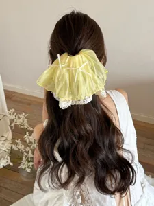 Back view of a model wearing a yellow French lace ruffle hair claw clip with bows