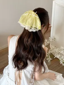 Back detail view showing a romantic yellow French lace bow hair claw clip on wavy hair