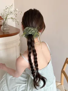 Achteraanzicht van een grote groene organza scrunchie met linten op een gevlochten haar