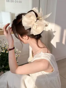 Detailopname van de grote crème organza strik haarklem in een elegant kapsel