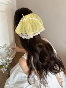 Detailed view of a yellow French lace bow hair claw clip styled on long wavy hair.