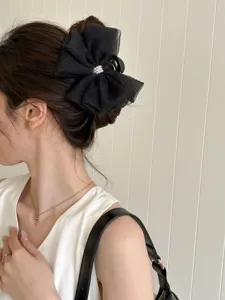 Vue détaillée d'une pince à cheveux à nœud en résille noire avec perles sur un modèle