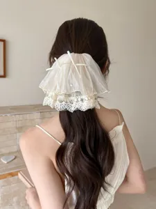 Rear view of an elegant French style lace bow hair claw clip styled on a low ponytail.