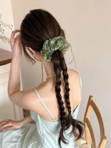 Achteraanzicht van een model met een grote groene mesh scrunchie met linten op gevlochten haar